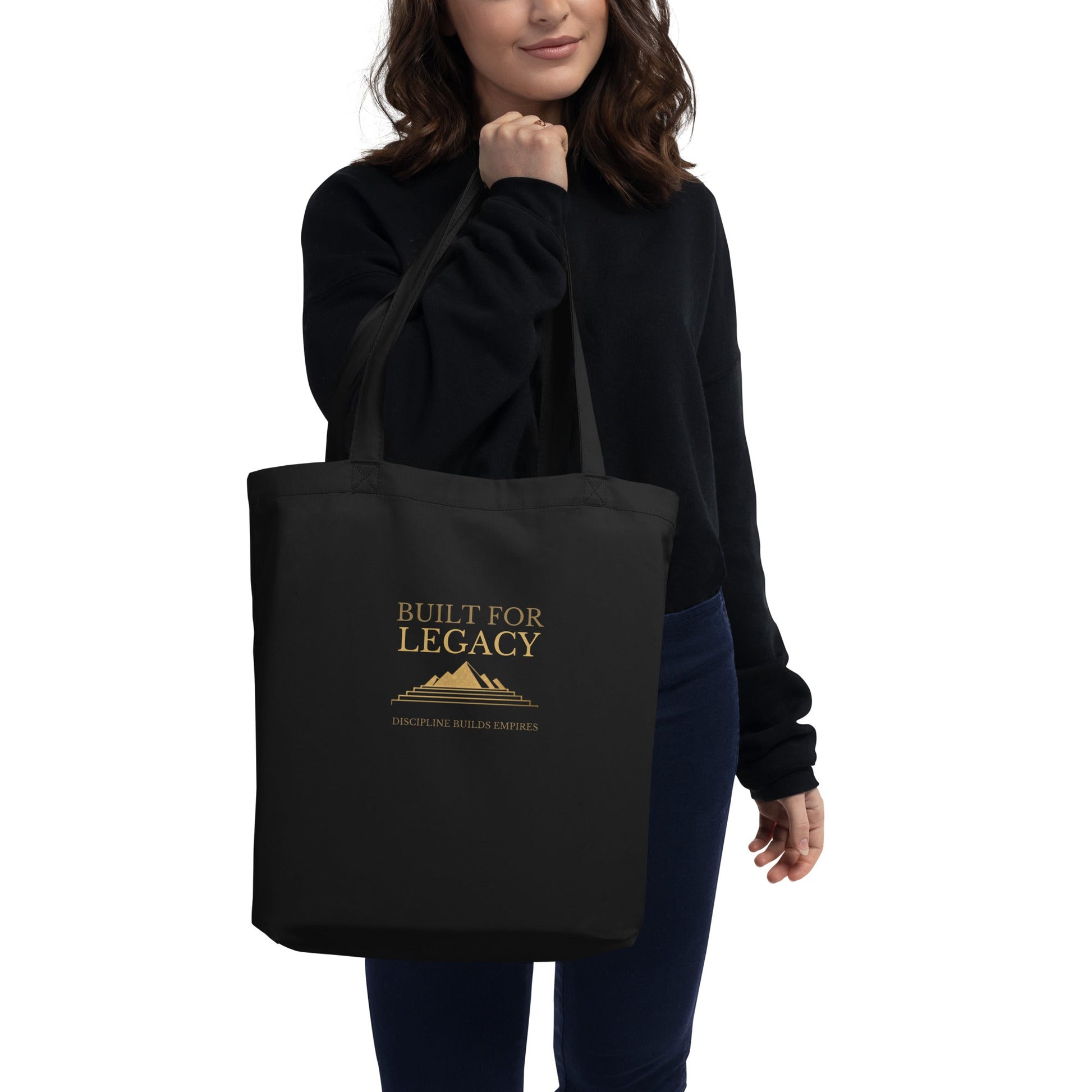 Black tote bag with “Built for Legacy” print, held by a person in a dark top