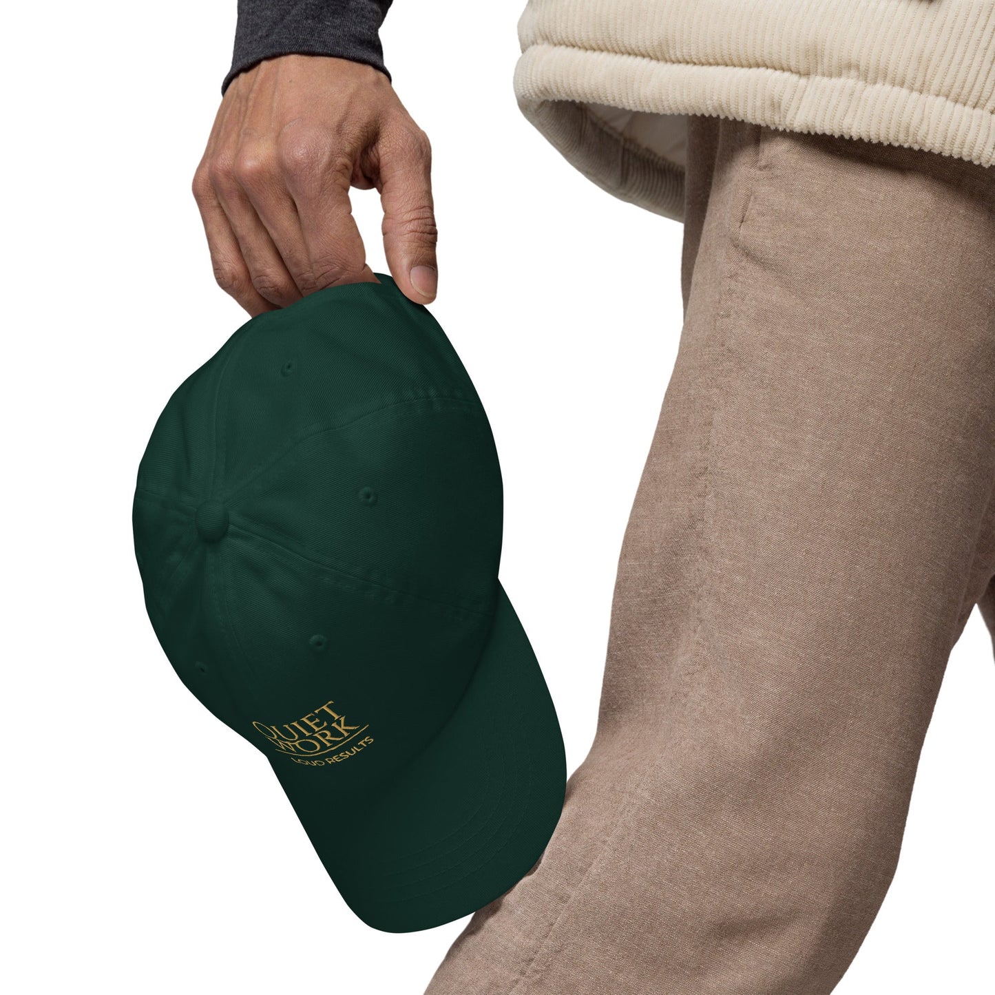 Dark green dad hat with curved brim and embroidered logo patch, held in hand