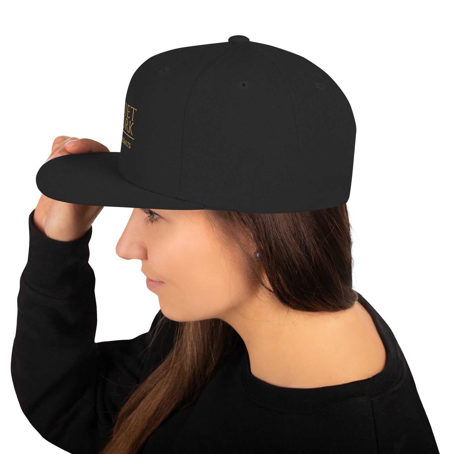 Black snapback cap shown from side with small logo embroidery